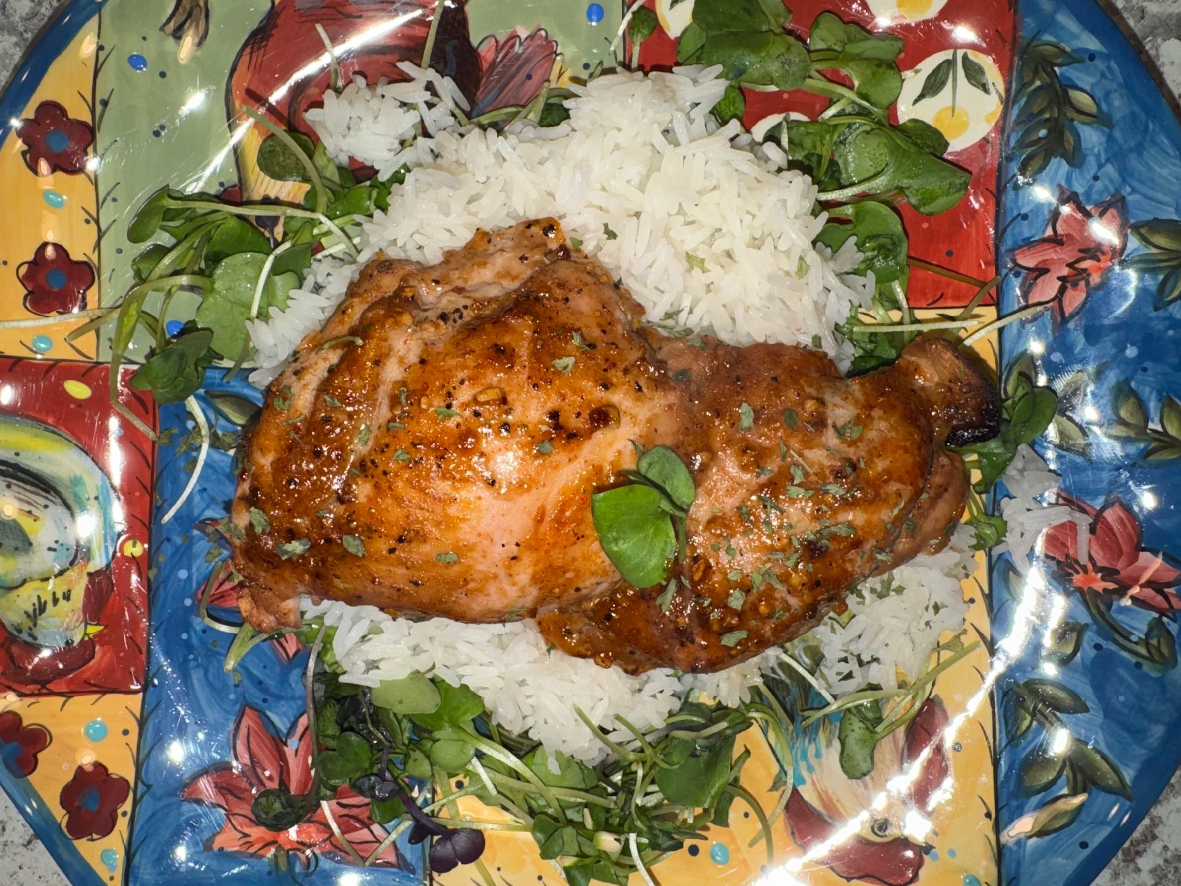 Grilled chicken leg served on a colorful plate with fluffy white rice and fresh herbs, showcasing a vibrant and appetizing meal presentation.